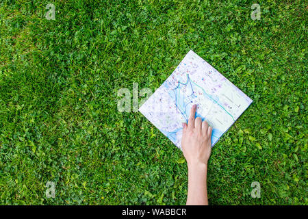 Billet sur la carte. Femme main montre un doigt sur une carte topographique sur l'herbe Banque D'Images