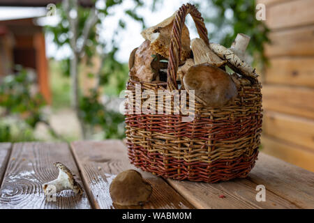 Un panier plein de champignons se dresse sur une table en bois sur la véranda d'une maison de pays de l'écotourisme. Banque D'Images