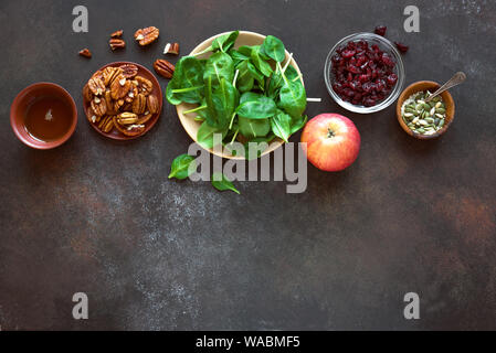 Les ingrédients de la Salade d'automne sain pour la cuisine de saison salade végétalienne saine - jeunes feuilles d'épinards, pommes, noix de pécan, les canneberges sèches, du miel sur rustic Banque D'Images