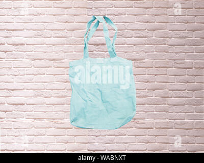 Mock up sac d'eco hipster tissu de coton blanc Sac shopping en brique blanche . bleu fond rustique de l'aedl Banque D'Images