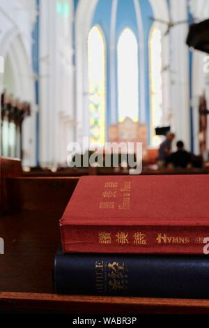 Singapour : Bible et livre de prières en chinois sur banc à Saint Andrew's Cathedral montrant l'intérieur de l'église et les fenêtres en arrière-plan Banque D'Images