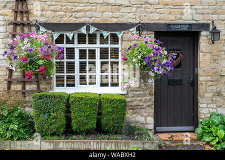 Paniers suspendus et banderoles à l'extérieur d'un chalet à Burford, Cotswolds, Oxfordshire, Angleterre Banque D'Images