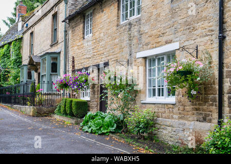 Paniers suspendus et banderoles à l'extérieur d'un chalet à Burford, Cotswolds, Oxfordshire, Angleterre Banque D'Images