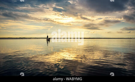 Belle nature paysage lumière dorée dans le ciel et silhouette pêcheur sur une petite embarcation utiliser des filets de pêche dans le matin au lever du soleil sur Songkhl Banque D'Images