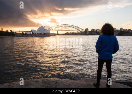 Veste hiver homme portant, regardant le port de Sydney, pendant le coucher du soleil Banque D'Images