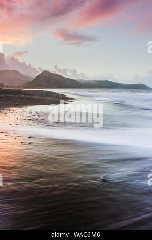 Coucher de soleil coloré magique sur une plage de sable fin avec rose violet ciel nuageux et la montagne dans l'arrière-plan Banque D'Images