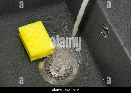 Pour l'éponge jaune foncé dans un shell. L'eau est recueillie dans l'évier. Close-up. Le nettoyage, le lavage de la vaisselle Banque D'Images