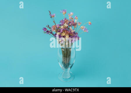 Magnifique bouquet de bleuets séchés dans un vase en verre sur un fond bleu turquoise Banque D'Images