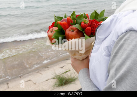 Girl est en attente sur le bord de la mer pour le retour de son petit ami avec un bouquet dans ses mains Banque D'Images