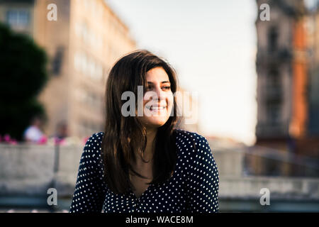 Belle jeune femme assise à l'extérieur, dans la ville aux beaux jours et à la suite Banque D'Images