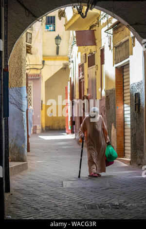 Vieille femme marocaine en descendant la rue étroite à Tanger with shopping bags Banque D'Images