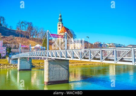 Salzbourg, Autriche - 27 février 2019 : le metal moderne Mullnsteg pont à travers la rivière Salzach mène à Mulln médiévale district, le 27 février à Salz Banque D'Images