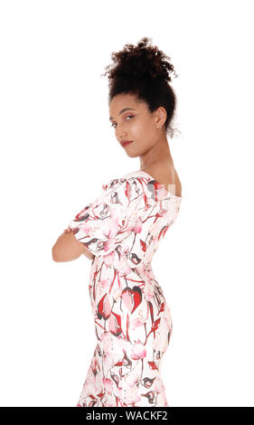 Une magnifique jeune femme multi-raciale debout dans une robe d'été de profil, avec les bras croisés, avec ses cheveux noirs frisés en chignon, isolée pour whi Banque D'Images