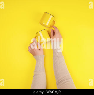 Deux tasses en céramique jaune sont pris en charge par une femme part sur un fond jaune, copy space Banque D'Images