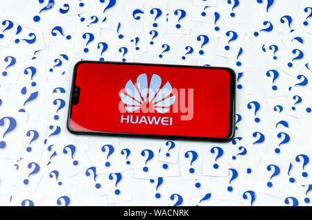 HUAWEI logo sur le smartphone HUAWEI et beaucoup d'interrogation autour du papier. La photo conceptuelle sur l'avenir de la technologie dans le géant US. Banque D'Images