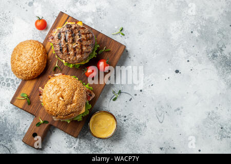 Grillé savoureux burger fait maison avec du boeuf, tomate, fromage, bacon et laitue sur un fond noir en lumière avec l'exemplaire de l'espace. Vue supérieure. restauration rapide et d'ordure Banque D'Images