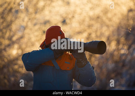 Lebedinyj Swan Réserve Naturelle, Russie - Février 23, 2019 : Un photographe avec un appareil photo et d'un téléobjectif tire sur un matin d'hiver glacial l'Altaï Banque D'Images