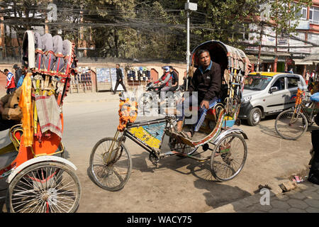 Pedicab driver attendent des passagers sur rue passante dans quartier de Thamel de Katmandou, Népal Banque D'Images