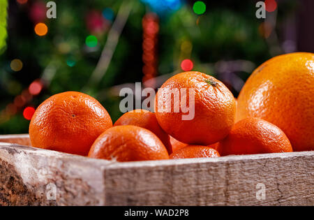 Mandarines Clémentines fraîches ou dans la boîte sur les lumières de Noël. Banque D'Images