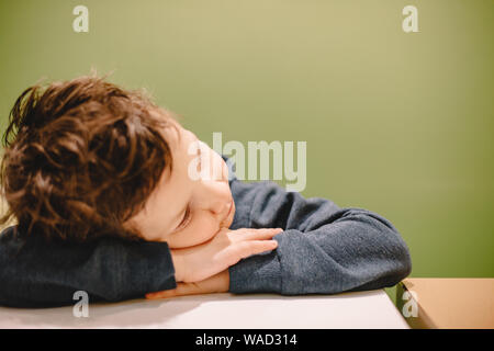 Boy leaning on desk contre fond vert Banque D'Images