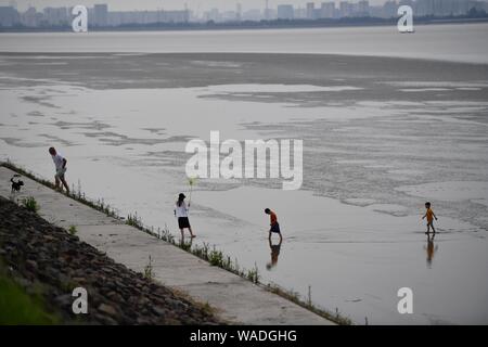 Les touristes jouer près d'une barrière sur les rives de la rivière Qiantang à Hangzhou, ville de l'est de la Chine dans la province du Zhejiang, le 8 juillet 2019. Une marée haute saison de t Banque D'Images