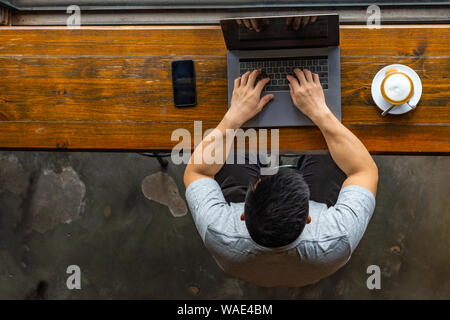 Asian man musclé freelancing sur ordinateur portable à la buvette rustique Banque D'Images