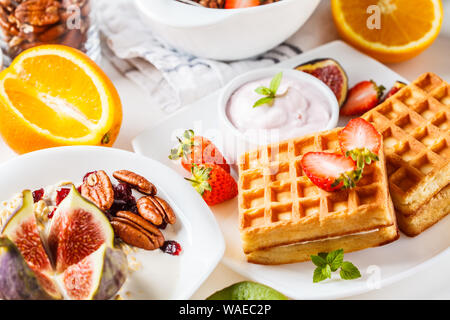 Table de petit-déjeuner avec du gruau, des gaufres, des croissants et des fruits. Arrière-plan blanc. Banque D'Images