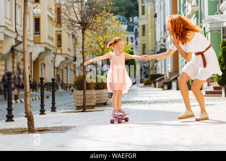 Heureuse petite fille debout sur son skateboard Banque D'Images