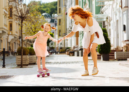 Heureux élève allant de la planche à roulettes avec sa maman Banque D'Images