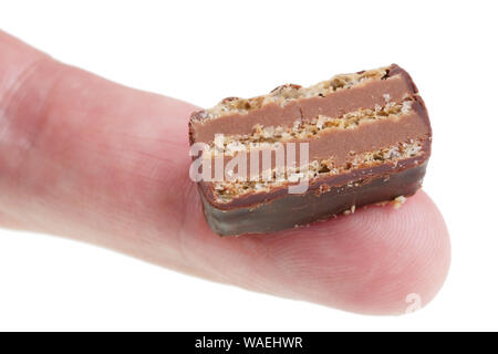 Dans le futur, nous allons manger ce concept - laid tranche de gâteau au chocolat sur le doigt. Isolé sur blanc macro studio Banque D'Images