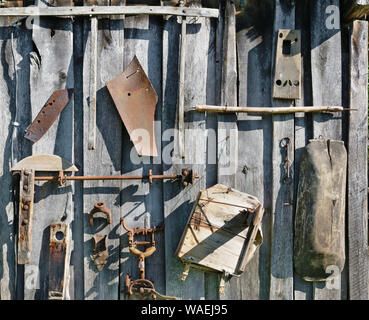 Sur le mur en bois de l'abri du village grange hang utilisé old rusty retro outils agricoles. Journée d'été ensoleillée vintage background Banque D'Images