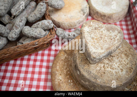 Cœur d'artisan du fromage et des saucisses, des produits typiques italiens, exposée sur une table dans un marché agricole local. Banque D'Images