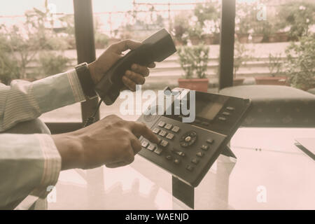 Close up of hand holding mâle récepteur du téléphone et composer un numéro de téléphone pour effectuer un appel à l'aide d'affaires pour discuter de téléphone fixe. Communic mondial Banque D'Images