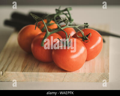 Close-up de 6 tomates fraîchement lavés prêt à être couper sur une planche de bois. Banque D'Images