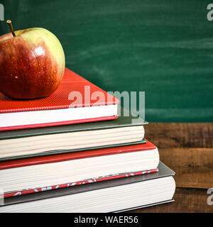 Livres et apple sur table en bois en face de l'école tableau. Concept Retour à l'école. Tons vintage photo. Banque D'Images