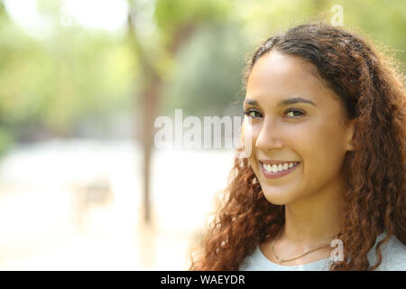 Beauty mixed race woman posing looking at camera avec sourire parfait dans un parc Banque D'Images