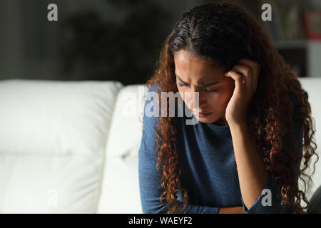 Triste mixed race woman se plaindre assis sur un canapé dans la salle de séjour à la maison Banque D'Images