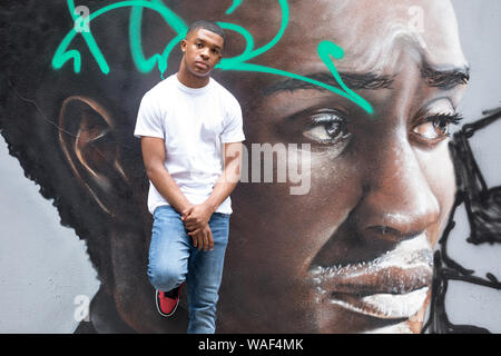 Un jeune homme pose devant un mur de graffiti portrait dans une rue de Londres Banque D'Images