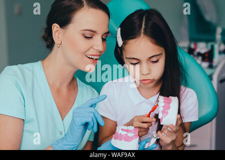 Smiling mixed race girl avec pédodontiste montrant bonne façon de brossage se brosser les dents Banque D'Images