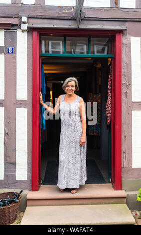 Hitzacker, Allemagne. 1er juillet 2019. Birgit Holsten en face de son magasin et est l'un des soi-disant Iselkaufkaufrauen dans la vieille ville de Düsseldorf. La vieille ville de Düsseldorf est situé sur l'Elbe, encadrée par deux bras de l'peu Jeetzel. Mais l'apparence idyllique a non seulement en voie de disparition à plusieurs reprises la zone connue sous le nom de city island. La vieille ville a été touchée par des inondations à plusieurs reprises, la dernière fois qu'elle a été inondée était en 2006. Credit : Philipp Schulze/dpa/Alamy Live News Banque D'Images