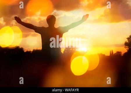 Silhouette d'un homme avec les mains posées dans le concept de religion, coucher de culte, de prière et de louange Banque D'Images