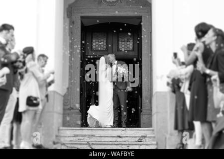 Les nouveaux mariés s'embrasser en sortant de l'église après la cérémonie du mariage, famille et amis à célébrer leur amour avec la douche de bulles de savon, personnalisé Banque D'Images