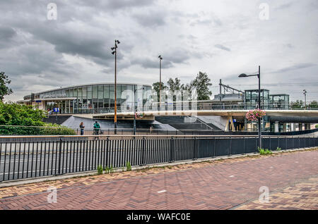 Helmond, Pays-Bas, 16 août 2019 : un pont pour les bicyclettes et les piétons traverse une rue animée sur la place de la gare, avec le nouveau chemin de fer stati Banque D'Images