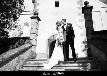 Le Baiser. Mariée et le marié embrasse tendrement sur un escalier en face d'une petite église locale. Banque D'Images