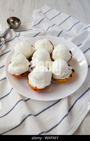 Pêches grillées faites maison avec de la glace à la vanille sur une plaque blanche, vue de côté. Banque D'Images