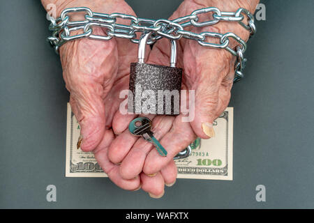 Mains d'une vieille femme 90 ans près. La clé et de la serrure, 100 dollars dans les mains d'une vieille femme. La vieille femme a les mains liées avec une chaîne. Banque D'Images