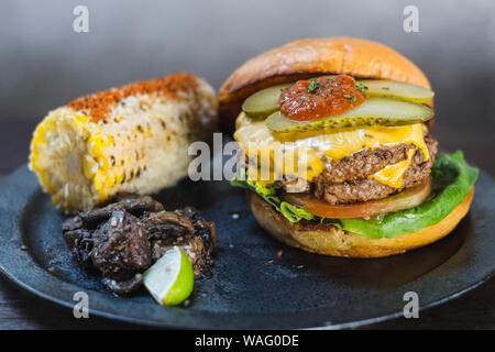 Burger All-American. Une chambre double et de graisse wagyu mélange chuck patty et bacon ketchup dans un pain brioché. Servi avec du maïs mexicain et thym sautés mushroo Banque D'Images