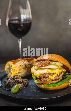 Burger All-American. Une chambre double et de graisse wagyu mélange chuck patty et bacon ketchup dans un pain brioché. Servi avec du maïs mexicain et thym sautés mushroo Banque D'Images