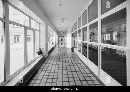 Vue à l'intérieur du corridor d'entrée , la vieille école ou immeuble, impasse longue et étroite passerelle et fenêtre en verre avec shin orange tôt le matin Banque D'Images