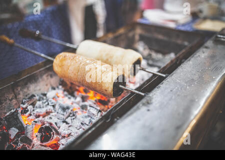 Gâteaux de cheminée (Kurtoskalacs) cuisson sur braise sur marché de Noël. Banque D'Images